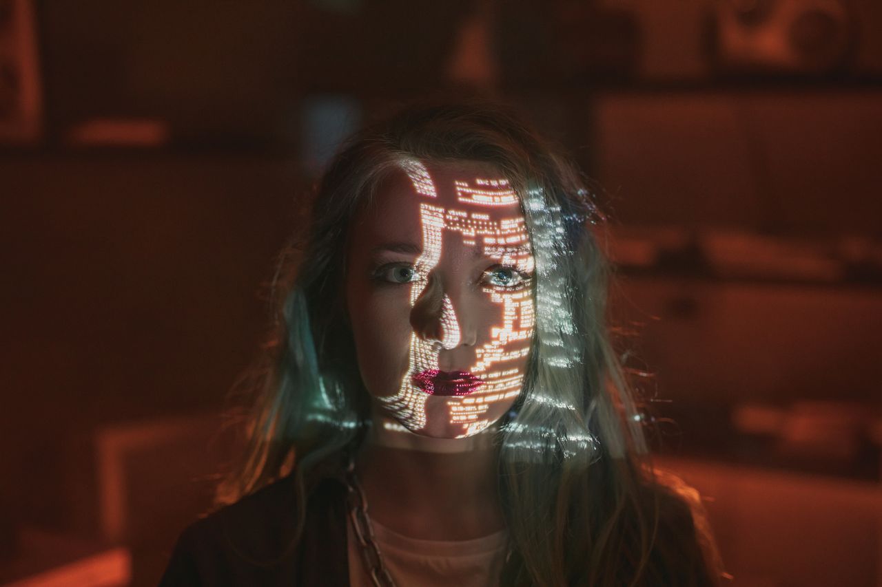 Words are projected on a woman's face. Her expression seems tense.