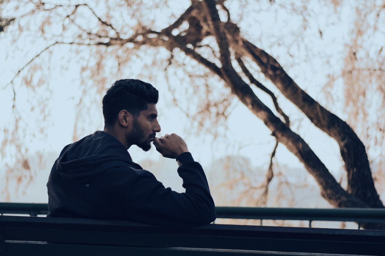 A man sits at a bench with a contemplative expression