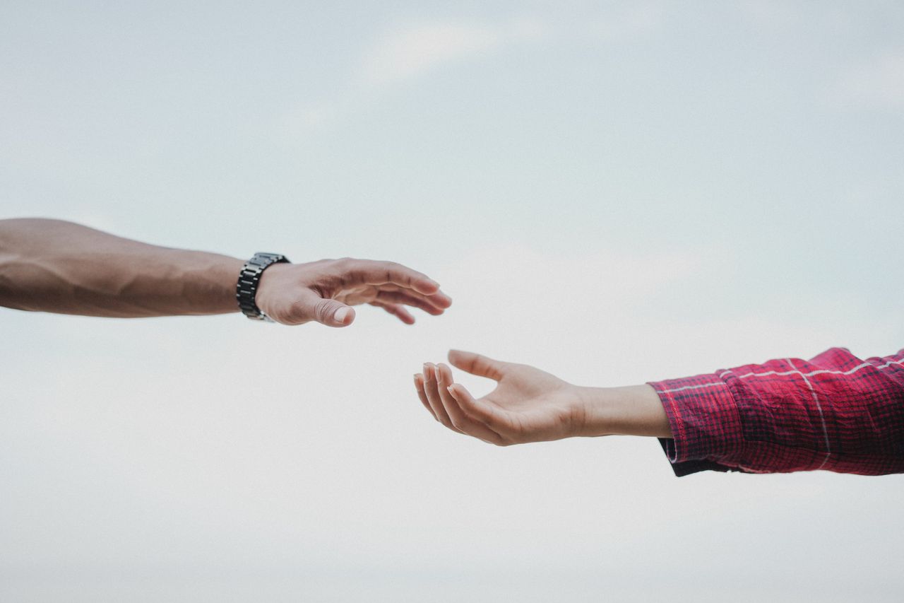 Two hands are outstretched toward each other but not quite touching